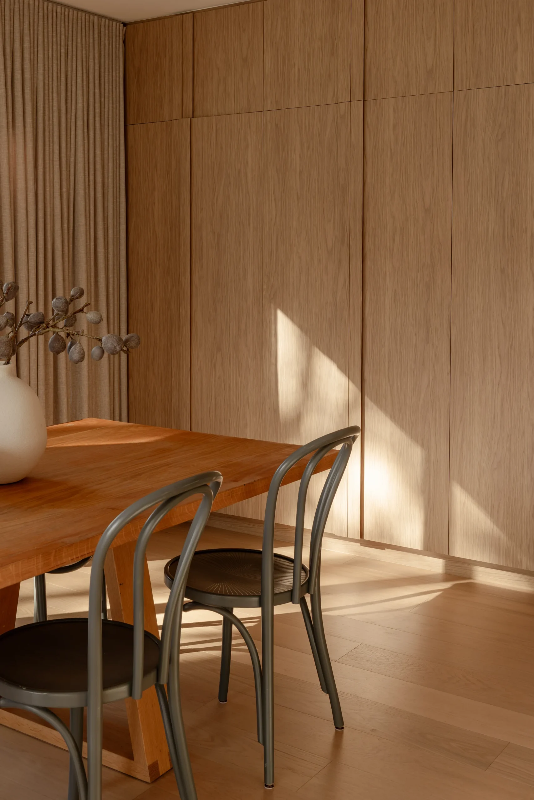 Timber dining nook with wood table, bentwood chairs and afternoon light on panelled wall