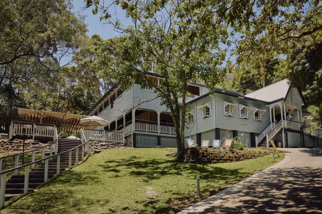Heritage Queenslander building with wraparound verandah, deck chairs and surrounding trees