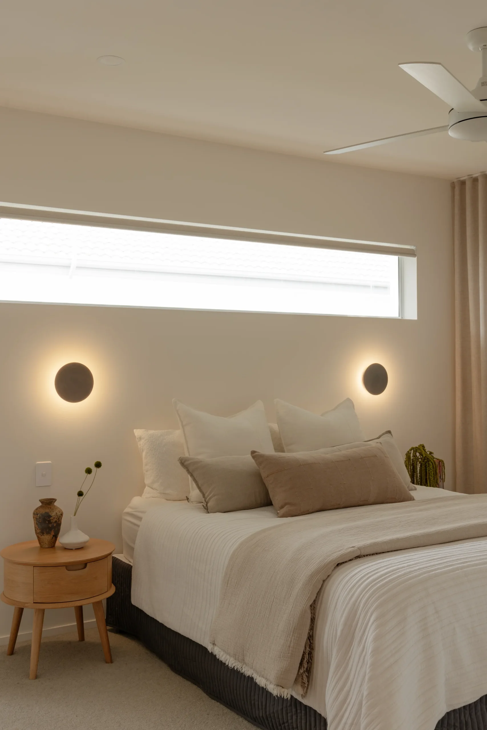Bed with round wall sconces and timber bedside table