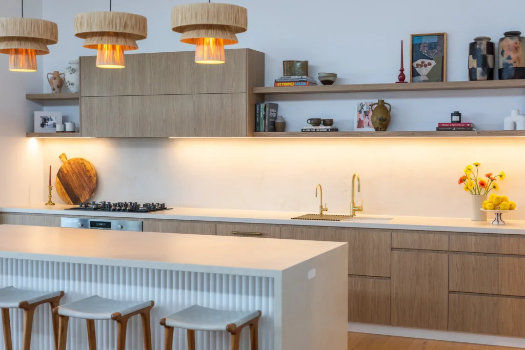 Kitchen with woven pendant lights and open shelving styled with ceramics
