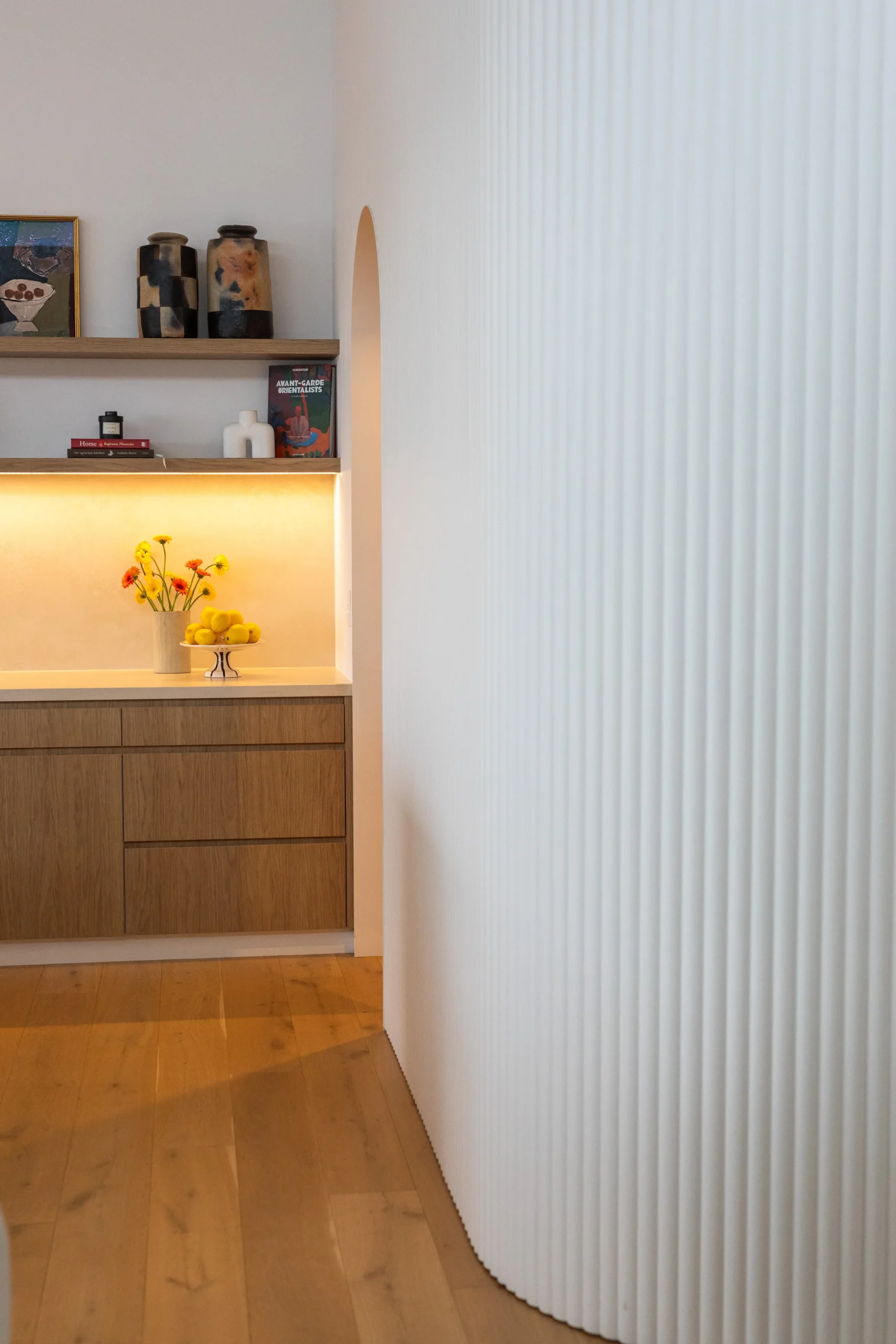 Curved fluted plaster archway leading into a styled kitchen nook