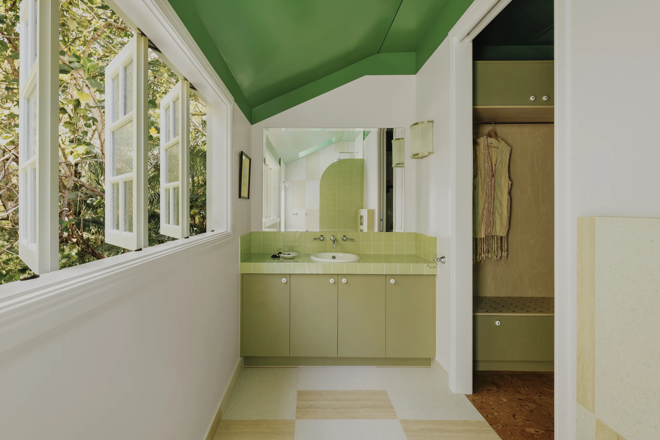 Green-tiled bathroom vanity with rainforest views through timber windows
