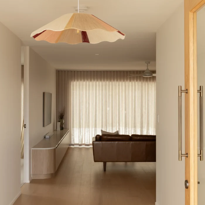 Hallway with statement scalloped pendant light leading to leather sofa