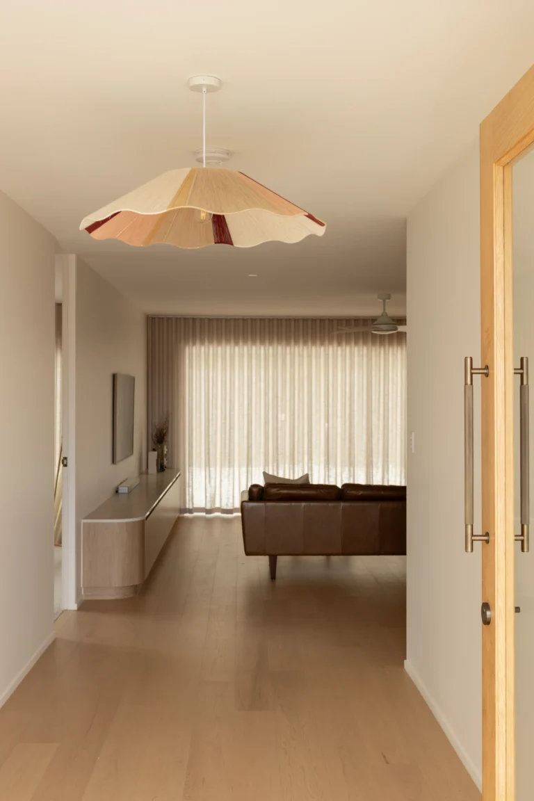 Hallway with statement scalloped pendant light leading to leather sofa