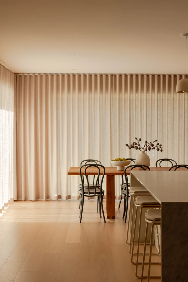 Dining area with sheer curtains, bentwood chairs and island bench